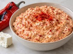 Купа с кремообразен урнебес от печени червени чушки и сирене, поднесен до печена чушка и парче бяло сирене.