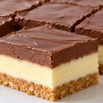 Двуцветен пудинг десерт с бисквитена основа Dvutsveten puding desert s biskvitena osnova, svetal vanilov sloy i shokoladov krem, narezan na kvadratni parcheta.