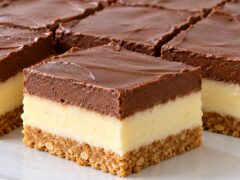 Dvutsveten puding desert s biskvitena osnova, svetal vanilov sloy i shokoladov krem, narezan na kvadratni parcheta.
